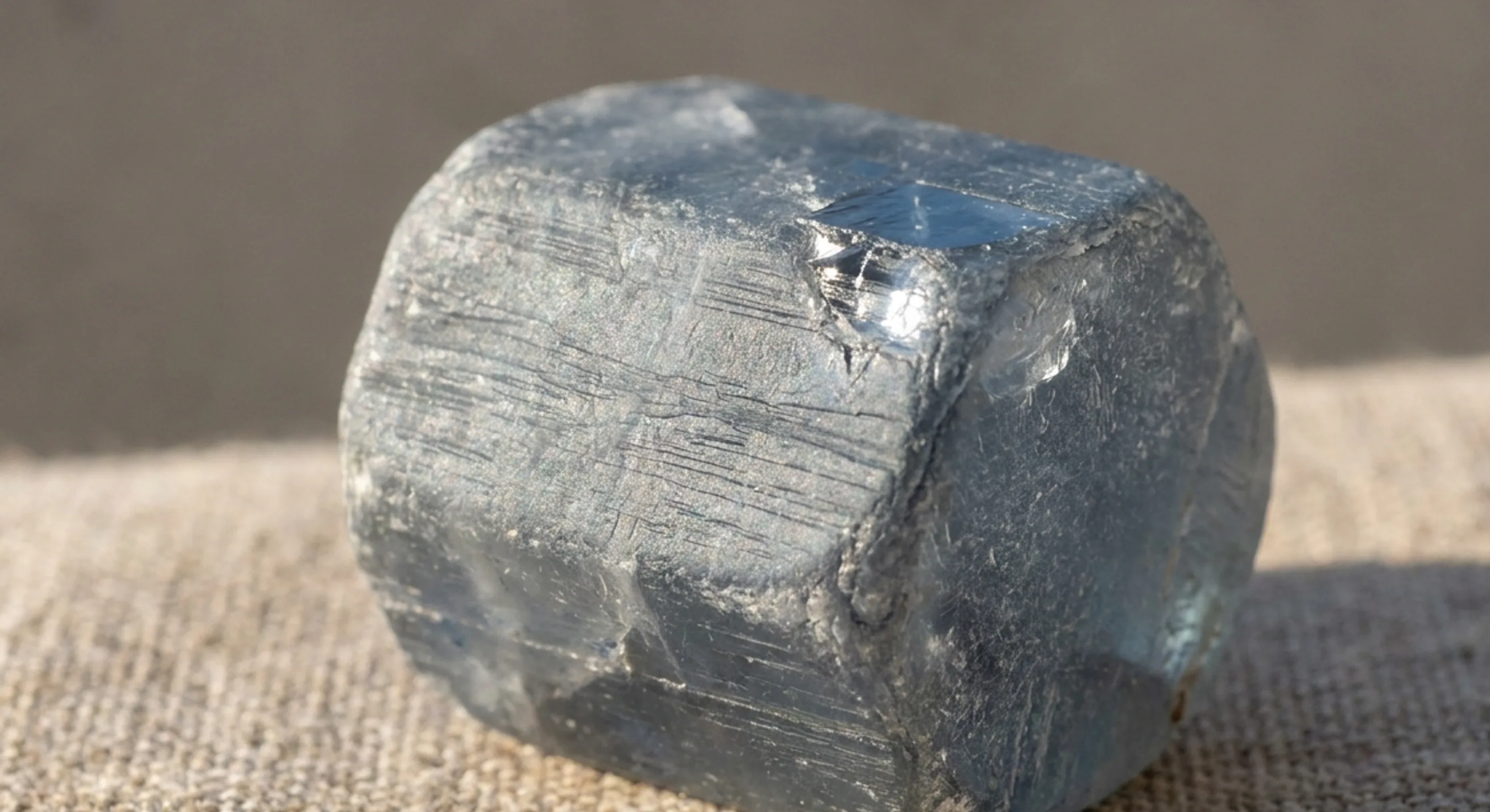 Macro of a single hexagonal rough sapphire crystal with horizontal striations and frosted edges