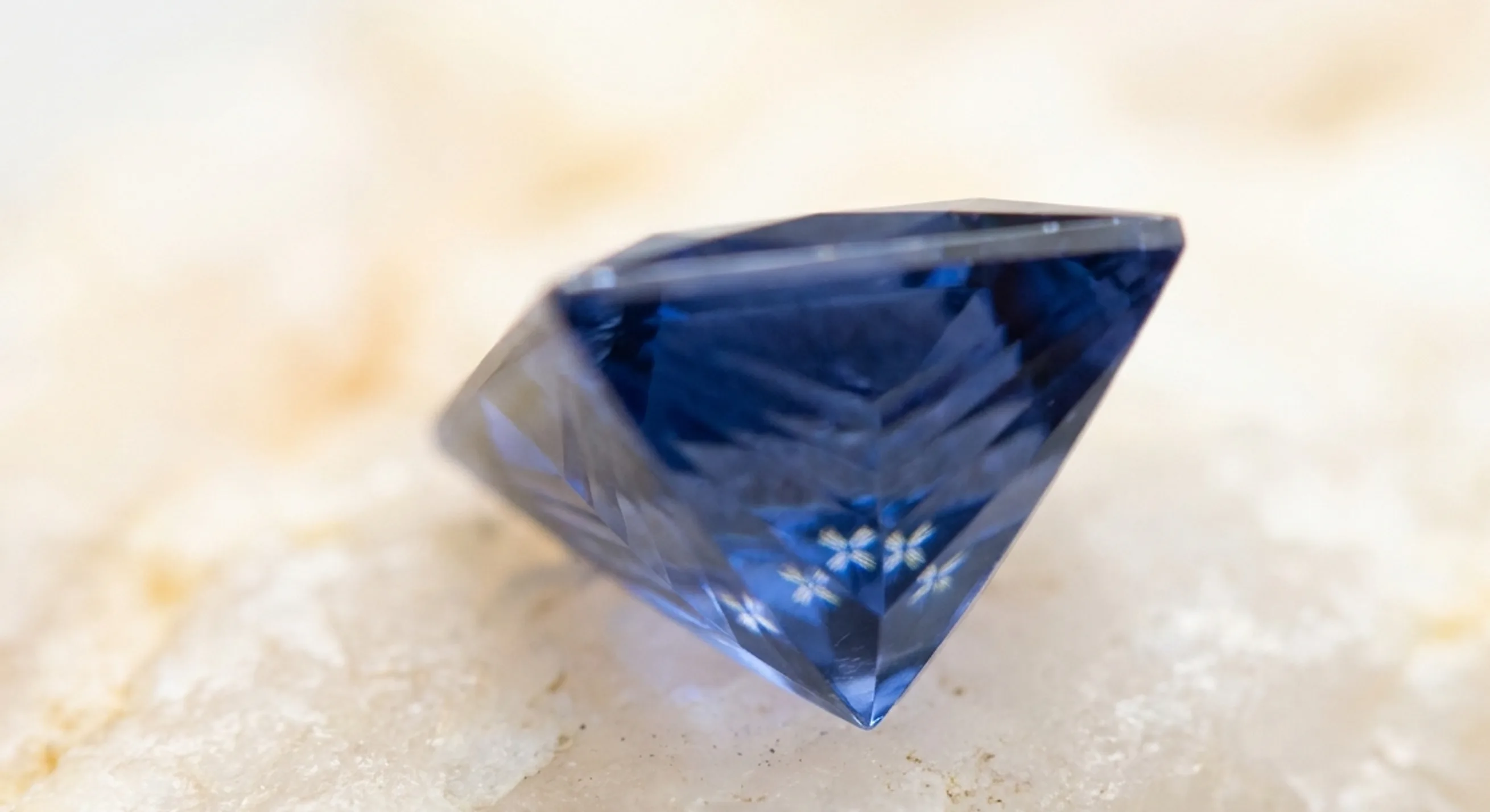 Side view of a princess-cut blue sapphire showing its inverted-pyramid pavilion of chevron facets