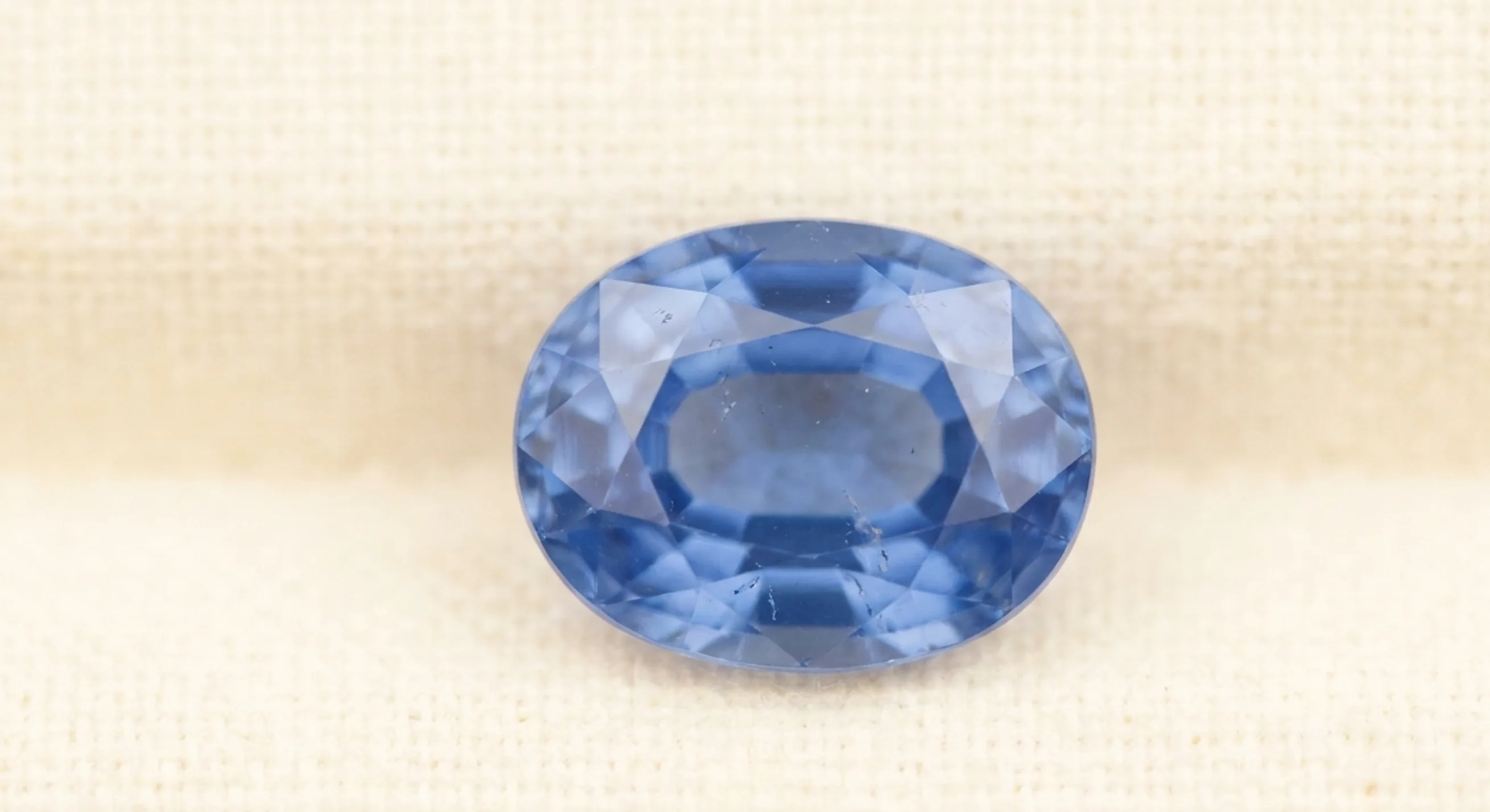 An oval blue sapphire seen face-up, with a soft bowtie shadow across its width